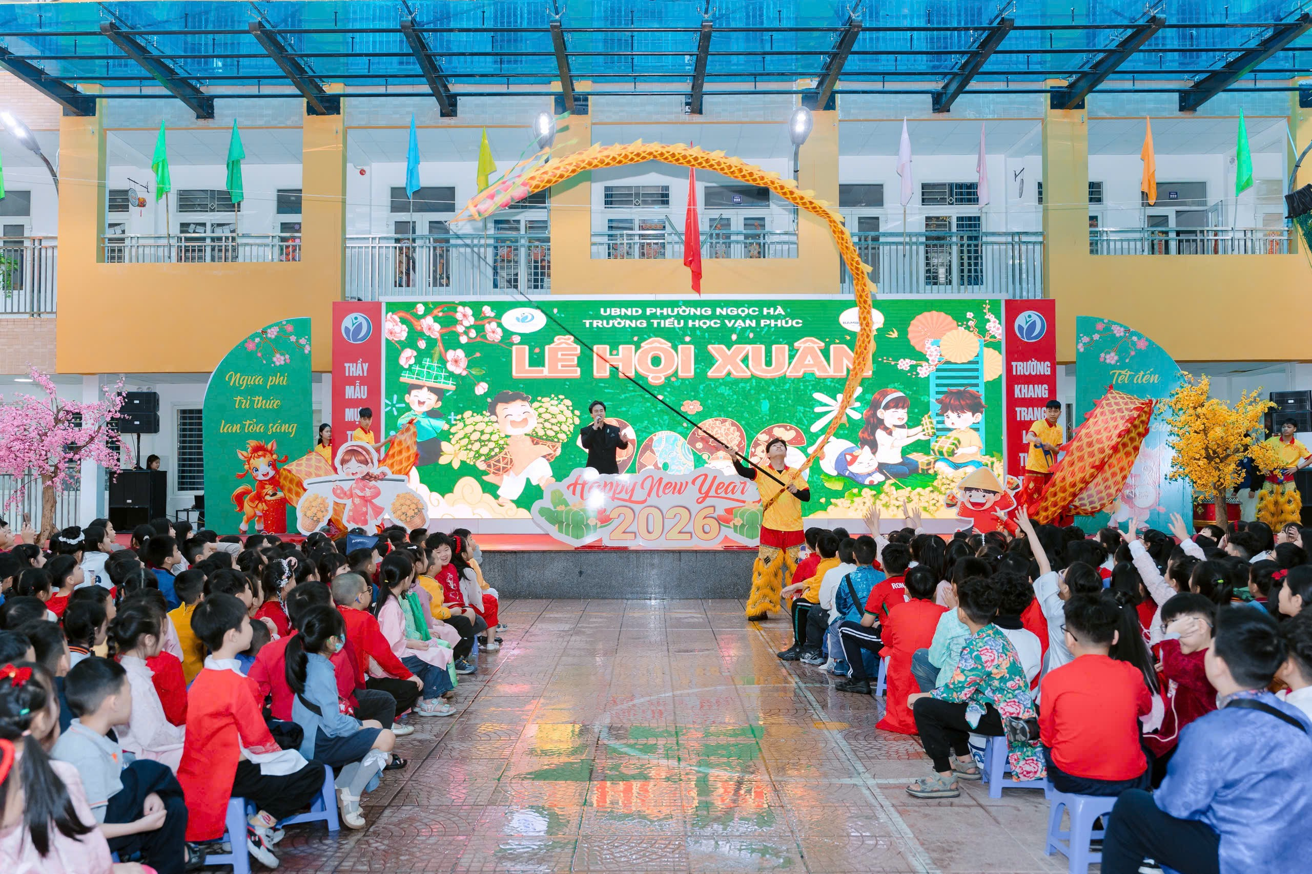 A group of people sitting in chairs in a room with a stage and a person playing a violin
Description automatically generated