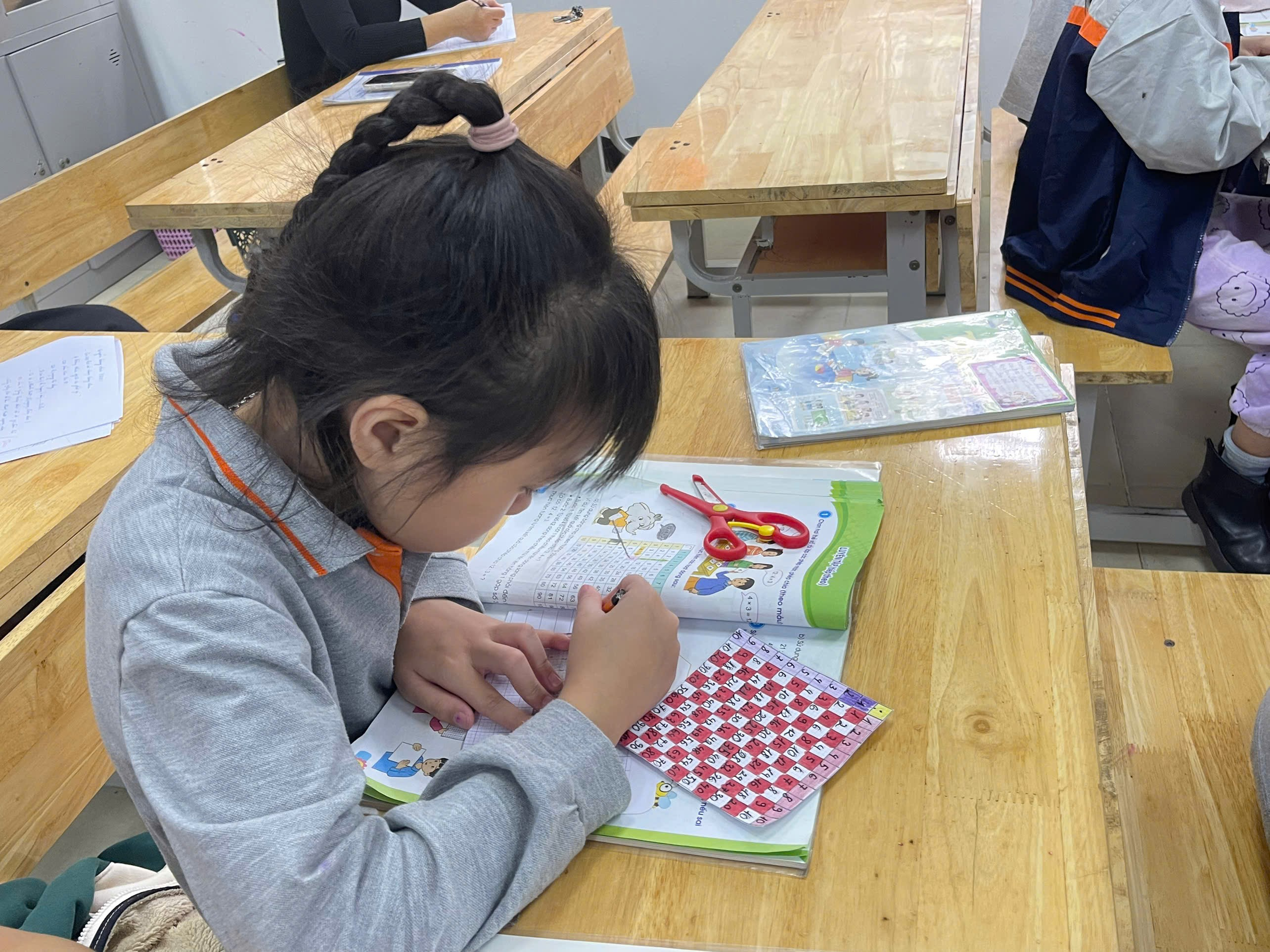 A child sitting at a desk writing on a book

Description automatically generated